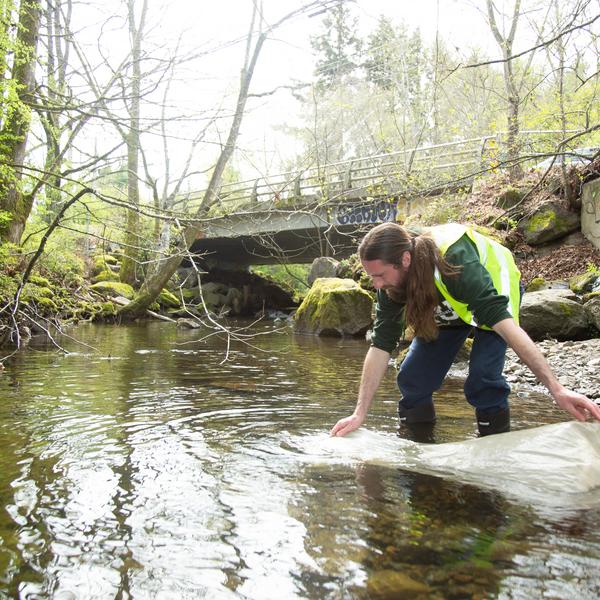 Student in chase river using a plankton tow net