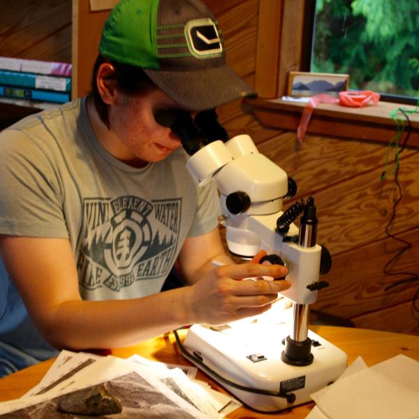 Student identifying rocks and minerals using a microscope