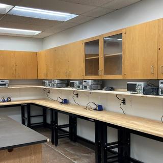 Student workbenches with function generator, multimeter, power supply, oscilloscope, and soldering station.